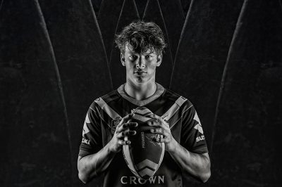black and white of young man holding a football, wearing a rugby top