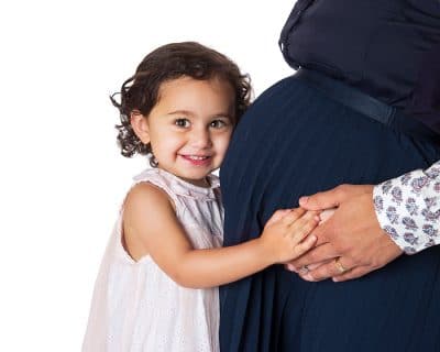 little girls hugging her mums pregnant tummy with a happy smile at Lifeworks Photography